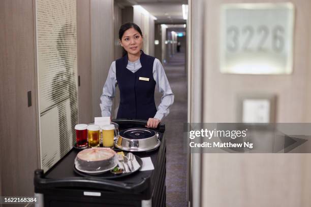 il personale dell'hotel asiatico porta il servizio in camera al cliente - servizio in camera foto e immagini stock