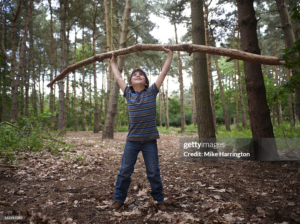 Young boy lifting branch in forest