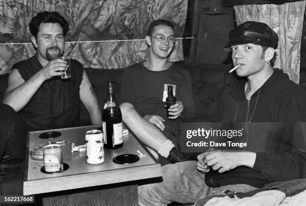 Northern Irish alternative rock band Therapy? sit at a table drinking on a tour bus, UK, circa 1993. Left to right: Andy Cairns, Michael McKeegan and...