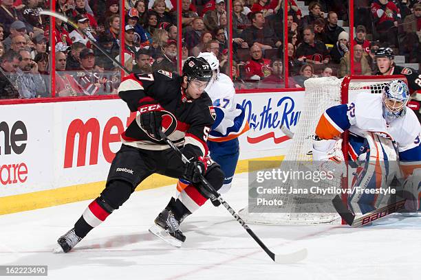 Derek Grant of the Ottawa Senators cuts towards the net with the puck as Andrew MacDonald and Rick DiPietro of the New York Islanders guard the net...
