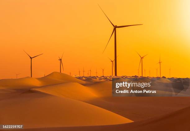 wind turbines in the desert with sand dunes. green energy concept. - united arab emirates stock pictures, royalty-free photos & images