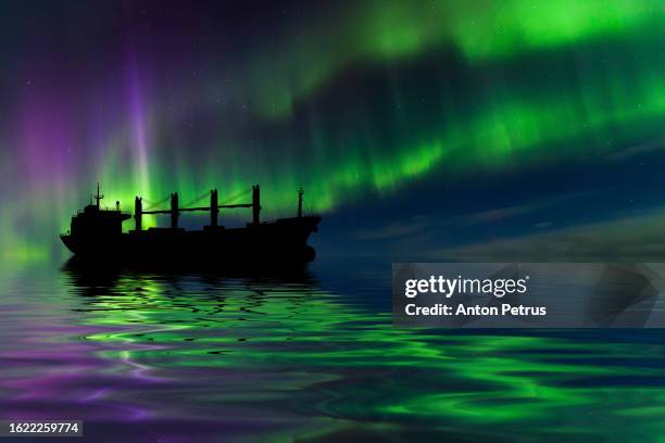 cargo ship at sea under northern lights - bulk carrier stock pictures, royalty-free photos & images