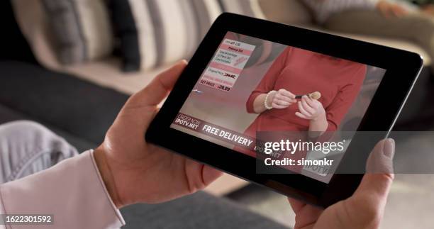 woman watching cosmetic products on digital tablet - home shopping stockfoto's en -beelden