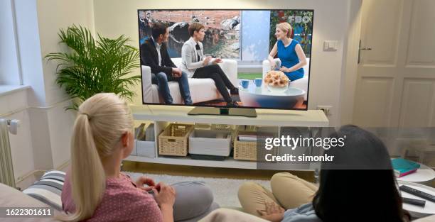 female friends watching tv at home - tv interview couch stock pictures, royalty-free photos & images