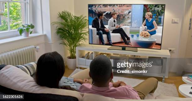 couple watching tv at home - television show stock pictures, royalty-free photos & images