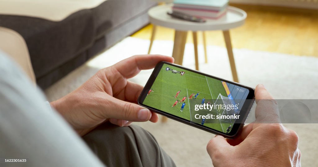 Mann, der Fußball auf dem Smartphone beobachtet