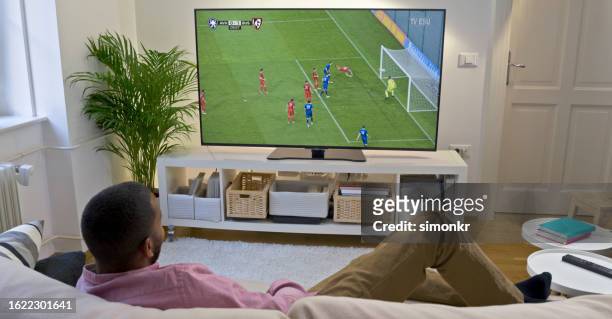 man watching football on tv - plasma stock pictures, royalty-free photos & images