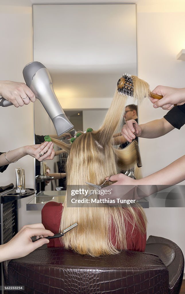 Hairdressers styling a female customer