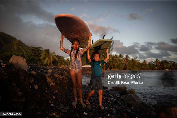 Children walk with their surfboards after surfing in Teahupo'o Bay on August 17, 2023 in Teahupo'o, French Polynesia. Teahupo'o has been hosting the...