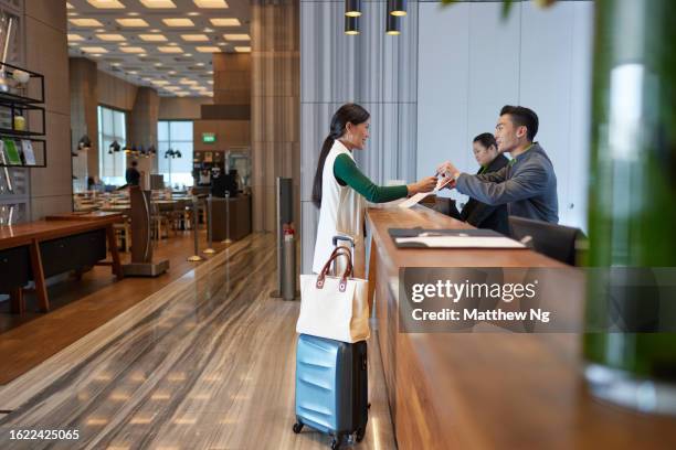 business travel - a beautiful asian female professional on business trip checking into the hotel - asian receptionist stock pictures, royalty-free photos & images