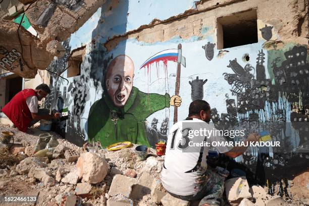 Syrian artists paint a mural on the wall of a house previously destroyed in an airstrike in Binnish in the rebel-held northwestern province of Idlib,...