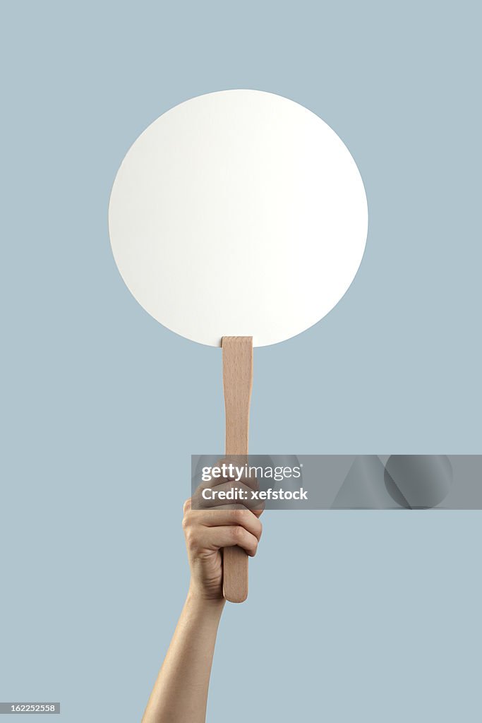 White auction placard with a hand holding it up