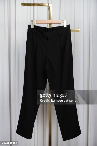 minimalist black pants on hanger - classic elegance personified - trousers stock pictures, royalty-free photos & images