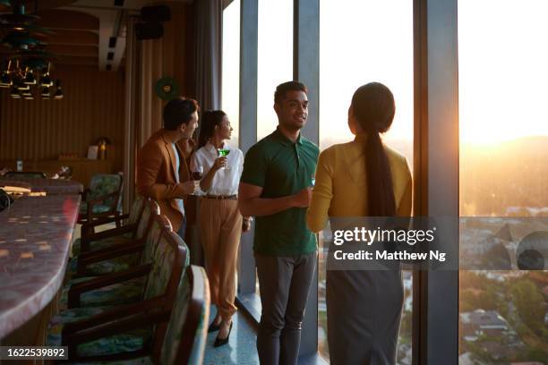beautiful asian businesswomen and businessmen meeting for drinks and chat at a bar after a conference event stock photo - singapore city people stock pictures, royalty-free photos & images