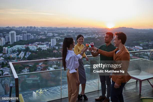 beautiful asian businesswomen and businessmen meeting for drinks and chat at a rooftop bar after a conference event - singapore city people stock pictures, royalty-free photos & images
