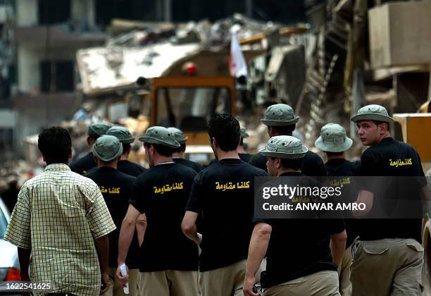 Zealots of pro-Iranian Hezbollah, wearing T-shirts written on them "We are all Resistance" walk in one of the destroyed areas of Beirut's southern...