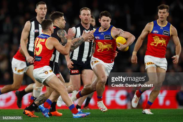 Lachie Neale of the Lions breaks a tackle attempt from Jamie Elliott of the Magpies during the round 23 AFL match between Collingwood Magpies and...