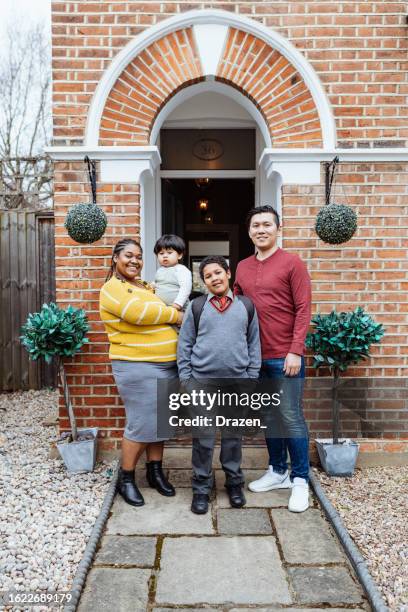 mixed family with two sons standing and looking at camera. family standing at porch while schoolboy leaving to school. - northern european descent stock pictures, royalty-free photos & images