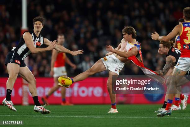 Deven Robertson of the Lions kicks the football whilst being tackled by his torn guernsey by Beau McCreery of the Magpies during the round 23 AFL...