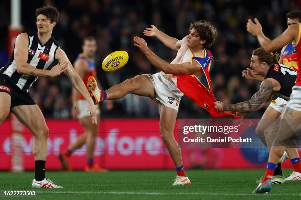 Deven Robertson of the Lions kicks the football whilst being tackled by his torn guernsey by Beau McCreery of the Magpies during the round 23 AFL...