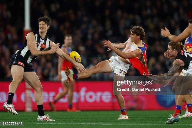 Deven Robertson of the Lions kicks the football whilst being tackled by his torn guernsey by Beau McCreery of the Magpies during the round 23 AFL...