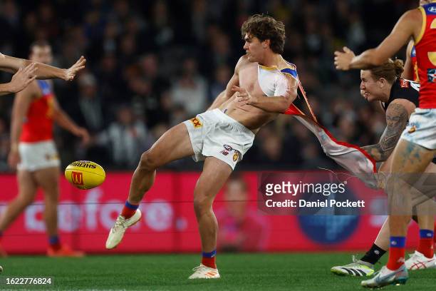 Deven Robertson of the Lions kicks the football whilst being tackled by his torn guernsey by Beau McCreery of the Magpies during the round 23 AFL...