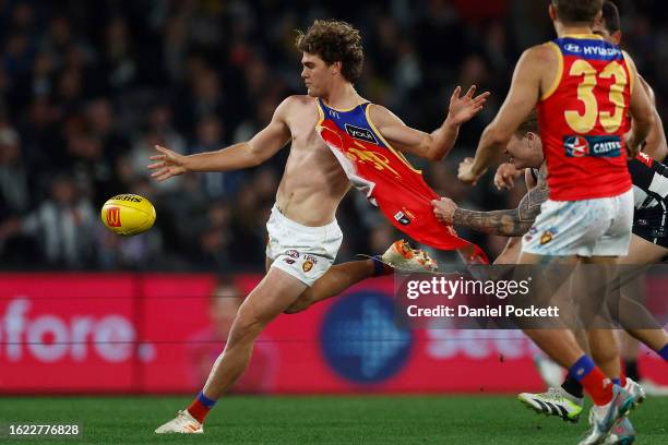 Deven Robertson of the Lions kicks the football whilst being tackled by his torn guernsey by Beau McCreery of the Magpies during the round 23 AFL...