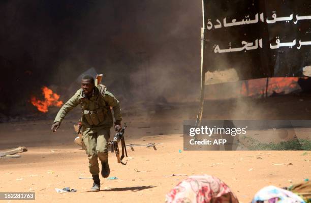 Malian soldier runs for cover as he fights after clashes erupted in the city of Gao on February 21, 2013 and an apparent car bomb struck near a camp...