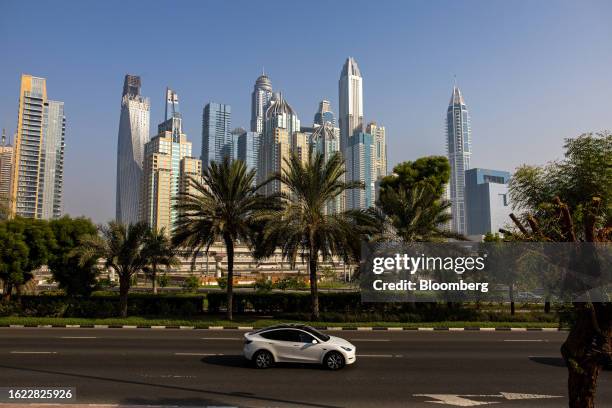 Tesla Inc. Electric vehicle drives past residential and commercial skyscrapers in the Dubai Marina district of Dubai, United Arab Emirates, on...