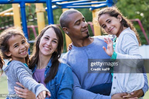famiglia di razza mista con due ragazze si divertono nel parco giochi - four people foto e immagini stock