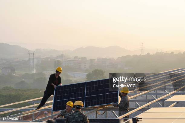 Technicians install solar panels on the roof of school buildings on August 18, 2023 in Loudi, Hunan Province of China.