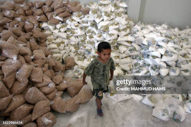 Young Palestinian boy takes bags of food aid from an office of the United Nations Relief and Works Agency for Palestinian refugees in Beit Lahia in...