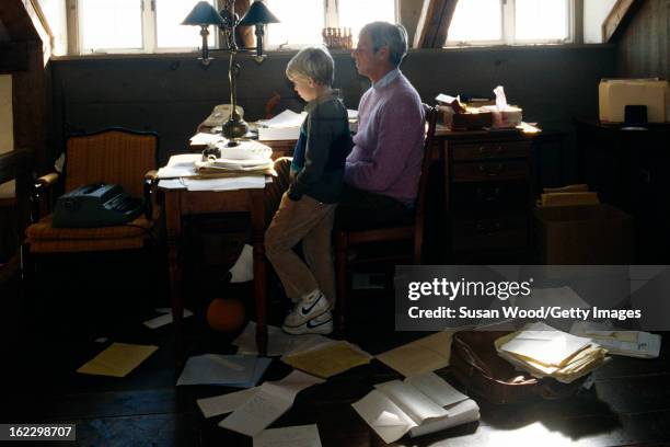 In the paper-strewn writing studio at his summer home, American writer and journalist George Plimpton at his desk with his son, Taylor Ames Plimpton,...