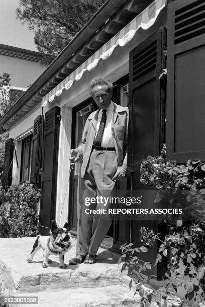 Jean Cocteau avec un faux chien devant sa maison sur la cote d'azur en 1955