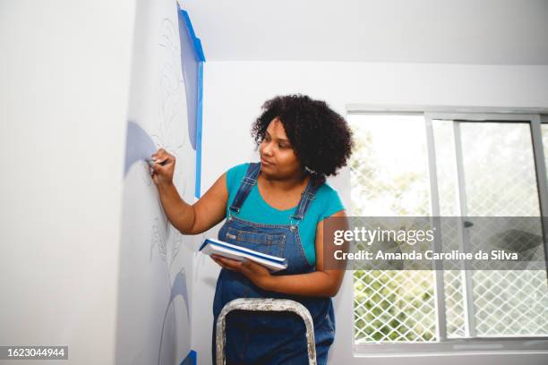 black brazilian woman does organic painting on the wall in the midst of a home renovation - reforma stock pictures, royalty-free photos & images