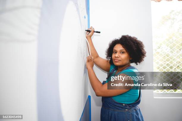 black brazilian woman does organic painting on the wall in the midst of a home renovation - reforma stock pictures, royalty-free photos & images