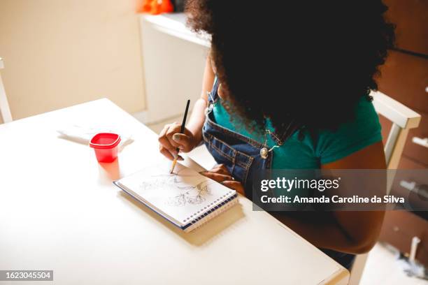 black brazilian woman sketching a design for the wall, a drawing of flowers, in a sketchbook - reforma stock pictures, royalty-free photos & images