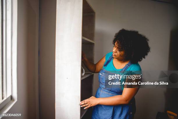 brazilian black woman painting a wooden cabinet in the middle of a renovation - reforma stock pictures, royalty-free photos & images