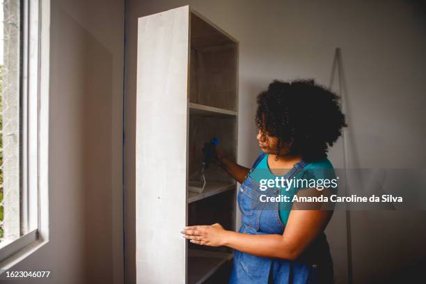 brazilian black woman painting a wooden cabinet in the middle of a renovation - reforma stock pictures, royalty-free photos & images