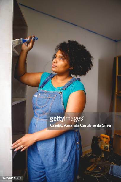 brazilian black woman painting a wooden cabinet in the middle of a renovation - reforma stock pictures, royalty-free photos & images
