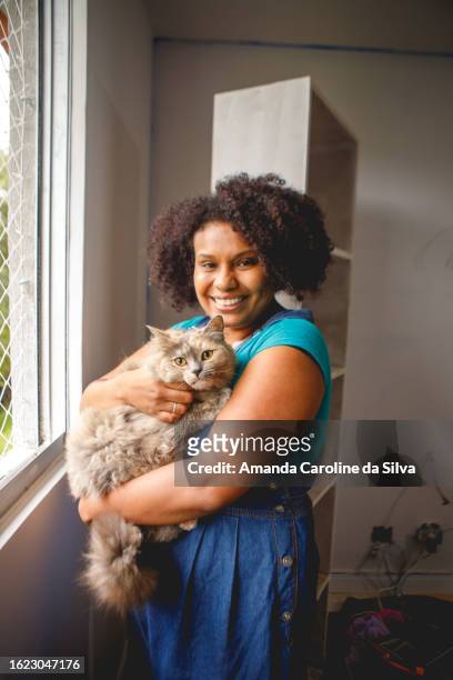portrait of black woman resting amid home renovations, petting her pet cat - reforma stock pictures, royalty-free photos & images