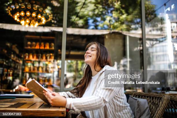 summer reading delight: happy emotional plus size woman enjoys a book at street cafe table, every day joy and copy space - hourglass books fotografías e imágenes de stock