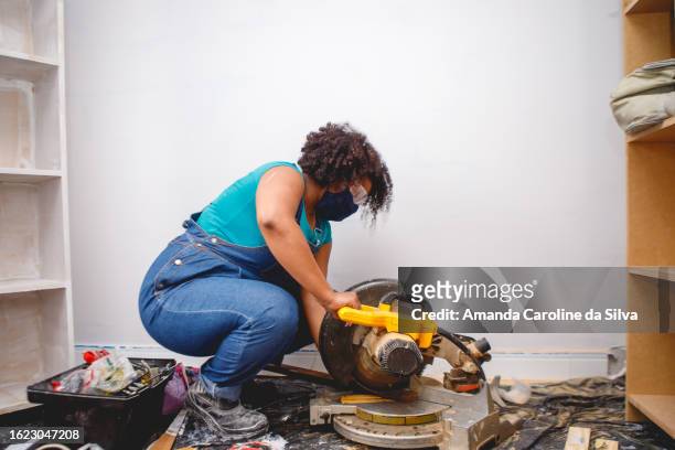 black brazilian woman working on home renovations, cutting piece of wood - reforma stock pictures, royalty-free photos & images