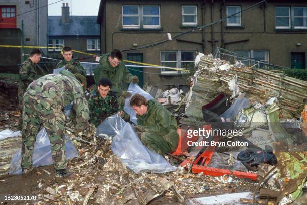 Members of the armed forces gather debris from Pan Am's flight 103, Clipper Maid of the Seas from the gardens of residential houses following the...