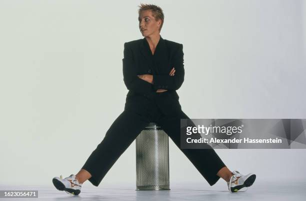 German athlete Grit Breuer wearing a black suit with running shoes, sitting with arms folded and her legs stretched out on either side of her seat,...