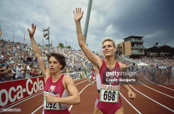 German athletes Grit Breuer and Katrin Krabbe, both wearing red-and-white Nike leotards, waving to spectators ahead of a sprint race during the...