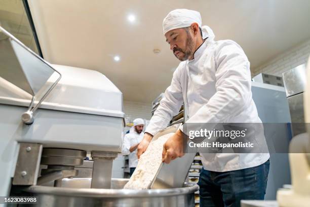 baker mixing flour while making bread at the bakery - baker flour stock pictures, royalty-free photos & images