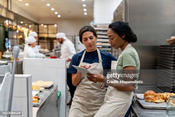 un boulanger forme un nouvel employé à la boulangerie - boulangerie industrielle photos et images de collection