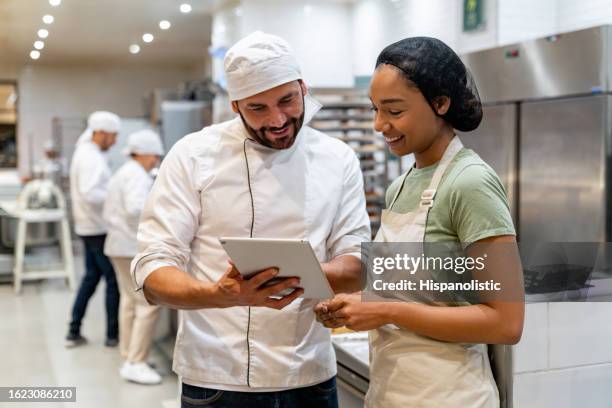 baker training a new employee at the bakery - food and drink industry stock pictures, royalty-free photos & images