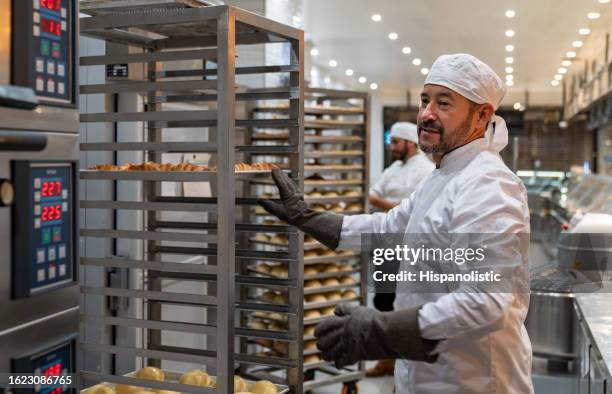 man working at a bakery making fresh bread - bread-oven stock pictures, royalty-free photos & images